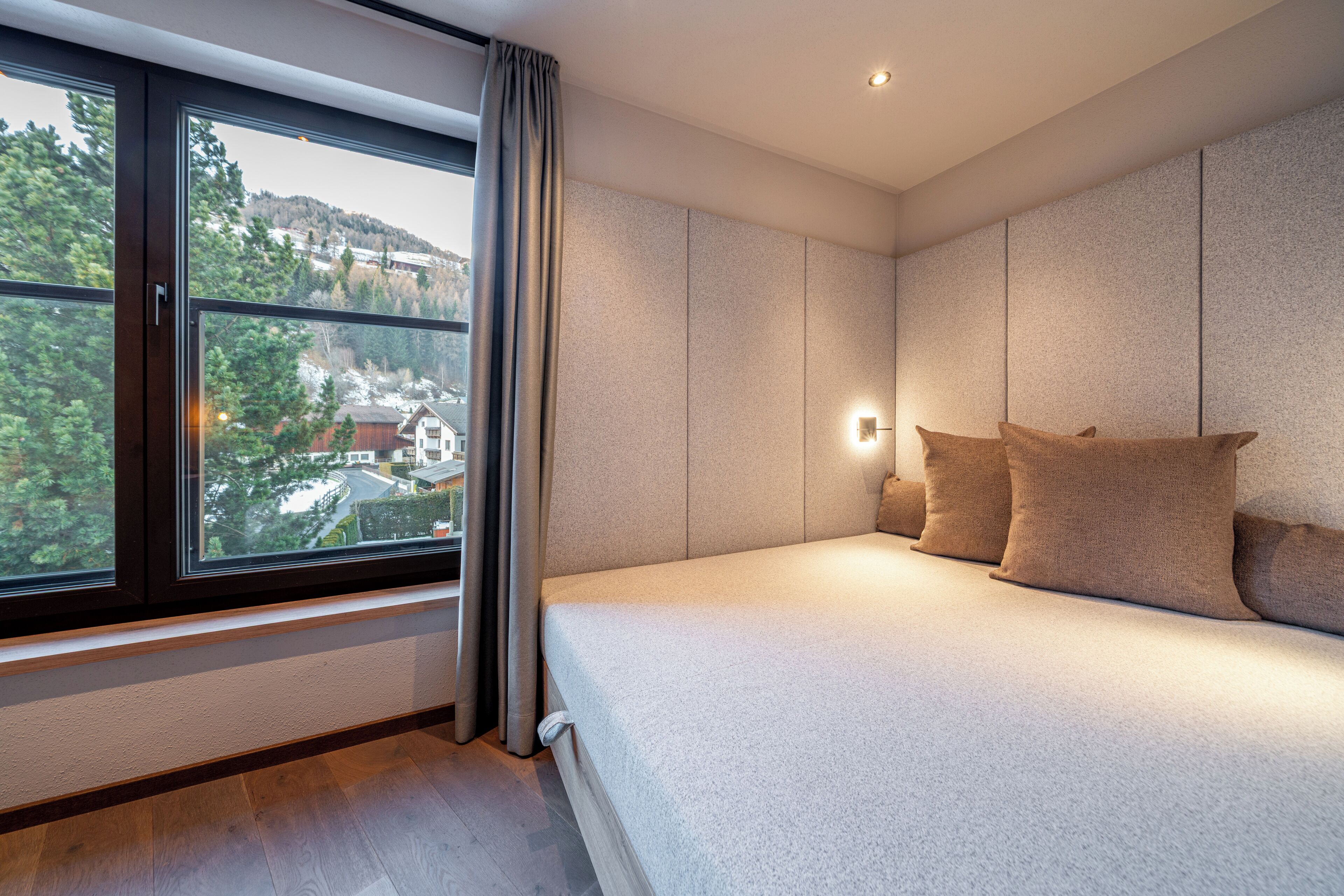 A bedroom with a large window, a bed, and a nightstand.