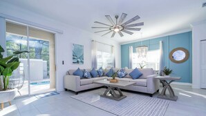 A spacious living room with a large sofa, a coffee table, and a ceiling fan.