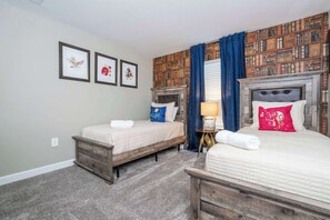 Une chambre avec deux lits, une bibliothèque murale et des tableaux encadrés.
