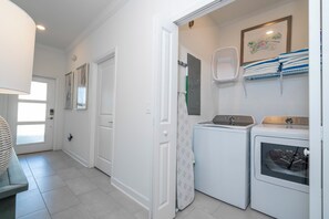 Une buanderie équipée d’un lave-linge, d’un sèche-linge et d’un étendoir sur lequel sont pliés des vêtements.