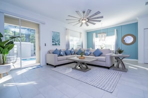 Un salon moderne avec un canapé gris, une table basse et un ventilateur de plafond.