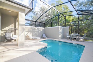 Une piscine extérieure couverte, dotée de chaises longues et d’une table.