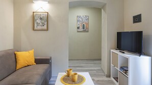 A living room with a sofa, a coffee table, a television, and artwork on the walls. - Raibetta Apartments by Wonderful Italy (Genoa)