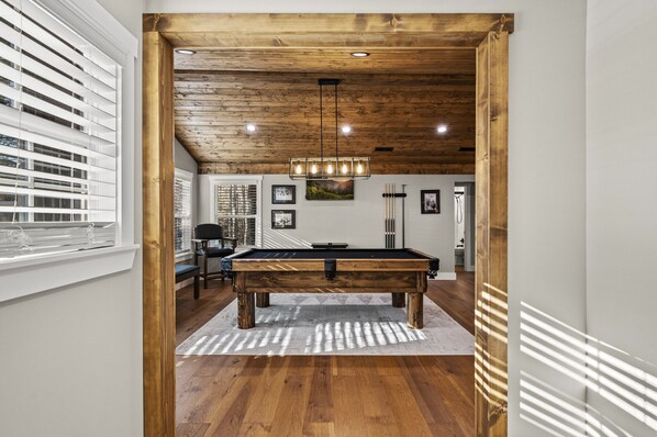 Una mesa de billar en una habitación con suelo de madera y techo inclinado.