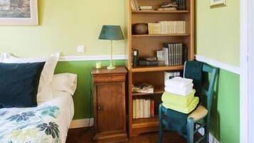 A room with a bed, a bookshelf, a chair, and a lamp.
