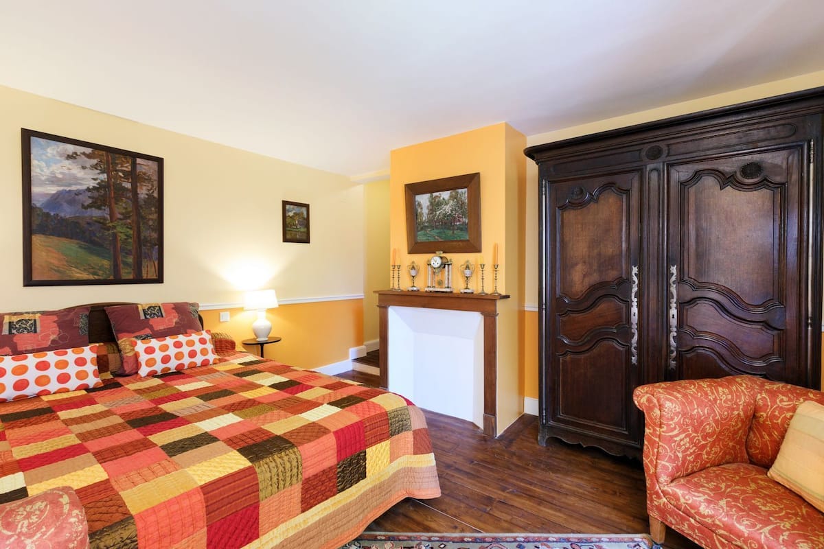 Ein Schlafzimmer mit einem großen Bett, einem Nachttisch, einer Kommode und einem Sessel.