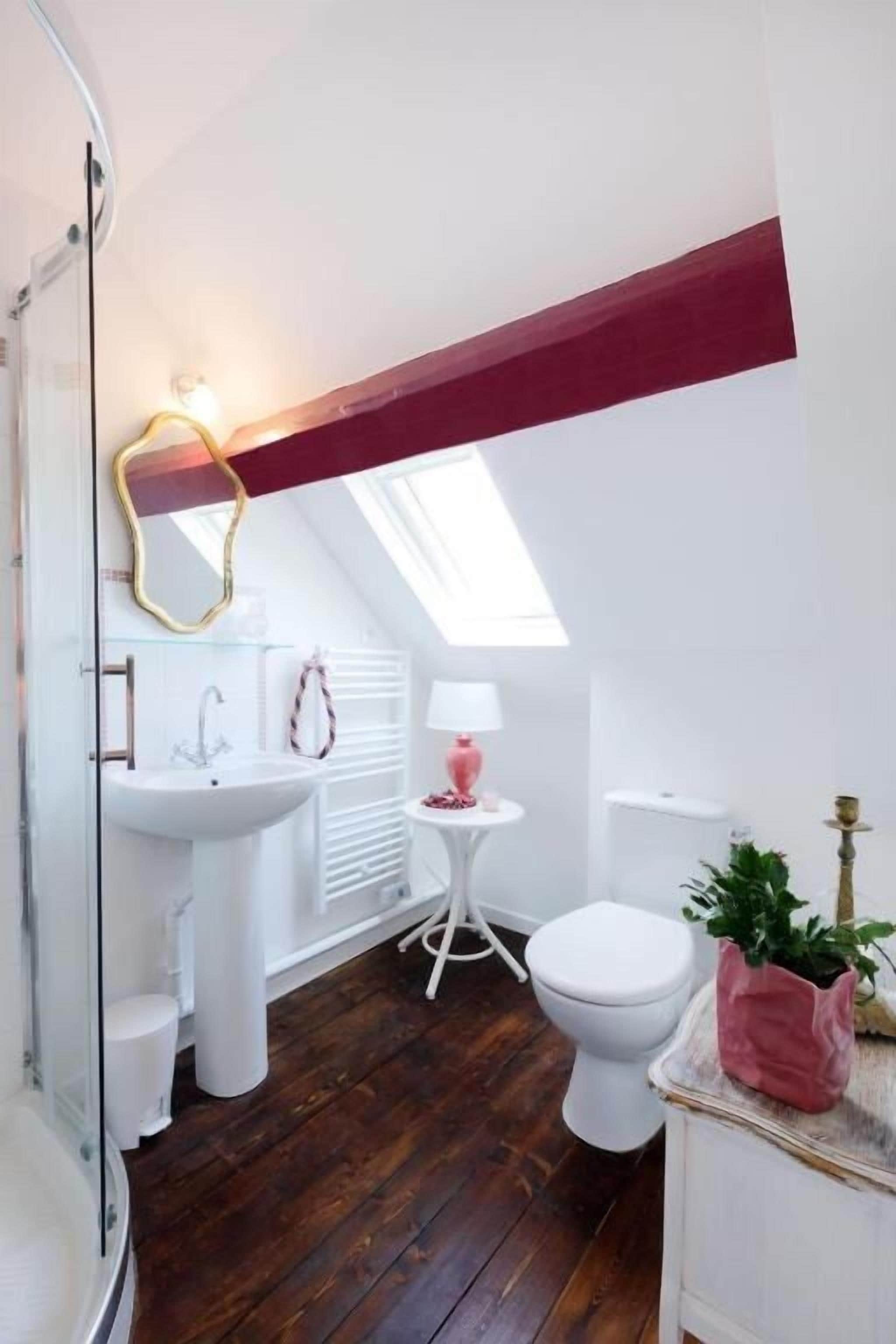 A modern bathroom with a skylight, white fixtures, and a wooden floor.