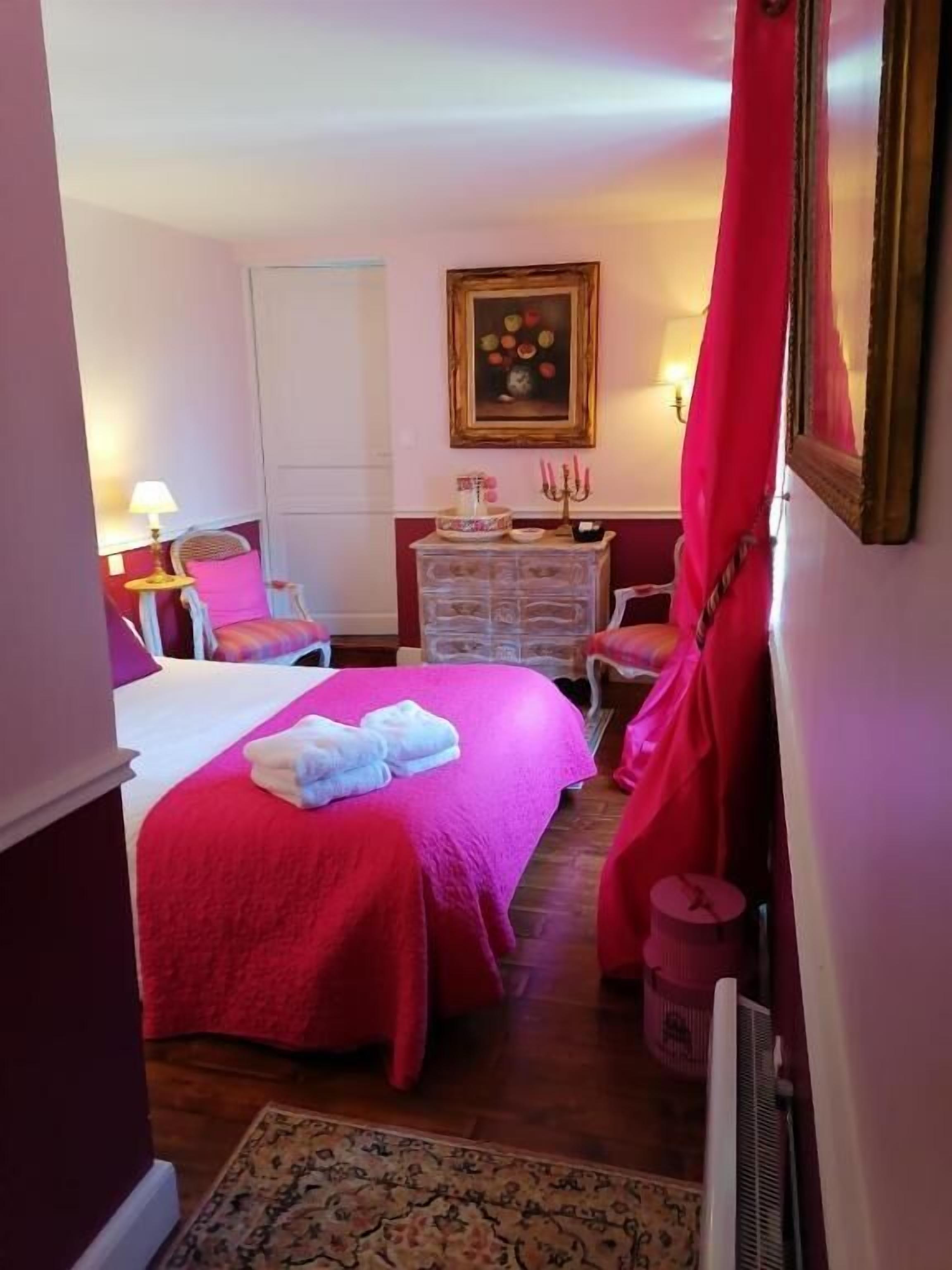 Un dormitorio con una cama grande, un aparador, una silla y un cuadro en la pared.