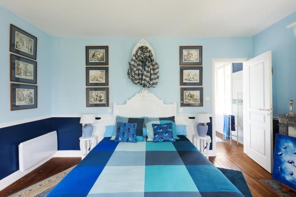 A bedroom with a checkered bedspread, a white headboard, and framed pictures on the walls.