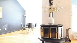 Un salon moderne avec une cheminée en noir et blanc, un vase rempli de fleurs et un coin repas avec des chaises.