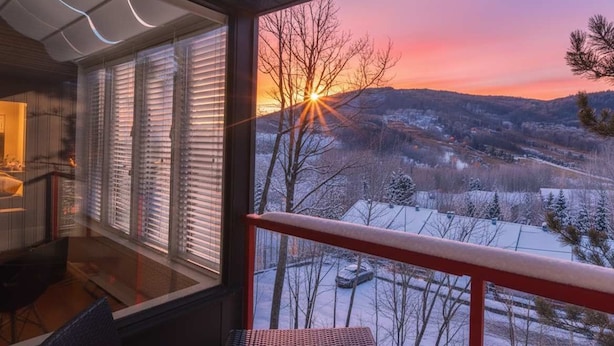 Un balcon offrant une vue sur un coucher de soleil se reflétant sur un paysage enneigé.