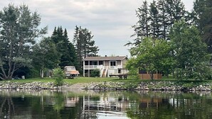 A house with a deck, a dock, and a pond.