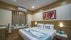 A hotel room with a wooden headboard, a bed with white bedding and blue patterned throw, a bedside table with a lamp, and an air conditioning unit on the ceiling. - Crimson Park Residency & Spa (Udaipur)