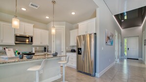 A modern kitchen with white cabinets, stainless steel appliances, and a bar area with stools. - VILLA MODERN TIMES – HEATED POOL | WATER VIEW | BOAT RENTAL + TOURS VOUCHER INCL. (Cape Coral)