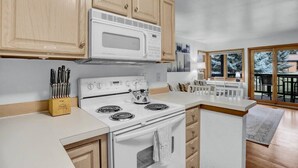 A modern kitchen with white appliances, wooden cabinets, and a view to the outside. - Pine Meadow Retreat (Steamboat Springs)