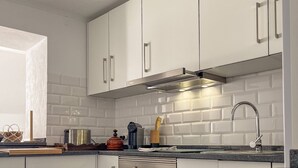 Una cocina moderna con gabinetes blancos, campana de acero inoxidable y encimera de granito.