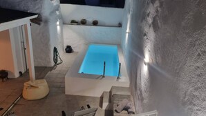 Una bañera con interior azul, una pared blanca con repisas y una pequeña planta en maceta.