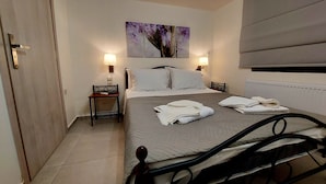 A bedroom with a bed, bedside tables, a nightstand, a wall-mounted painting, and a radiator. - Cozy suite, by Spyros & Marina, near to the city centre & old venetian harbour  (Chania)