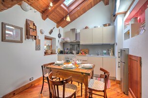 Una cocina acogedora con vigas de madera, una mesa de comedor preparada para cuatro personas y un refrigerador.
