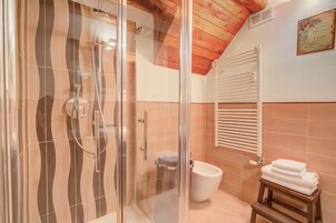A bathroom with a glass-enclosed shower, a toilet, and a towel rack.