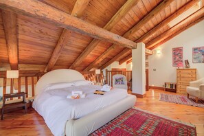 A bedroom with a wooden ceiling, a large bed, a chair, a dresser, and a rug. - Romito Lodge Apartment Mountain Retreat (Cesana Torinese)