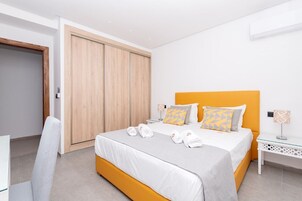 Une chambre moderne avec un grand lit, une armoire en bois et une table de chevet avec une lampe.