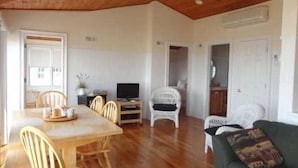 Een ruime woonkamer met een houten eettafel, stoelen, een televisie en een bank.