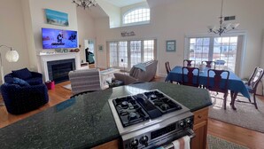 A spacious living room with a fireplace, a dining area, and a kitchen with a gas stove.