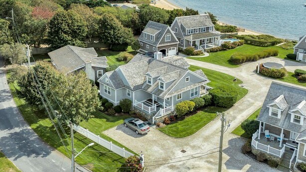 A residential area with houses, a driveway, and a beach in the background.