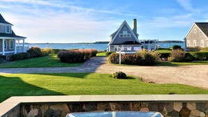 A coastal property with a well-maintained lawn, a stone pathway, and a view of the sea.