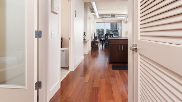 A modern interior with a wooden floor, a kitchen area with a sink and cabinets, and a view through a door. - Pet Friendly 2 Bedroom And Apartment Near Rittenhouse Apts by RedAwning (Philadelphia)