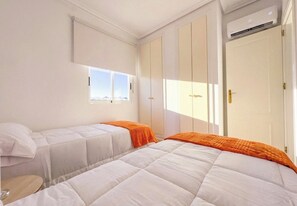 Ein Hotelzimmer mit zwei Betten, einem Fenster, einer Klimaanlage und einem Kleiderschrank.