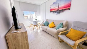 A modern living room with a sofa, armchair, and a flat-screen TV on a wooden stand.
