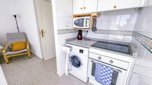 Eine kleine Küche mit Mikrowelle, Toaster, Wasserkocher und Waschmaschine.