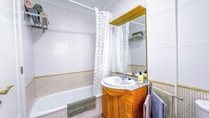 Ein Badezimmer mit einer Badewanne, einem Waschbecken mit Spiegel und einem Handtuchhalter.
