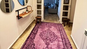 Ein Flur mit einem violetten Teppich, einem Regal mit einer kleinen Pflanze und einem Spiegel an der Wand.