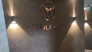 Uma área de recepção com um logotipo, espaço para sentar e piso coberto de carpete.