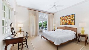 Ein Schlafzimmer mit Bett, Schreibtisch, Stuhl, Deckenventilator und einem Bild an der Wand.