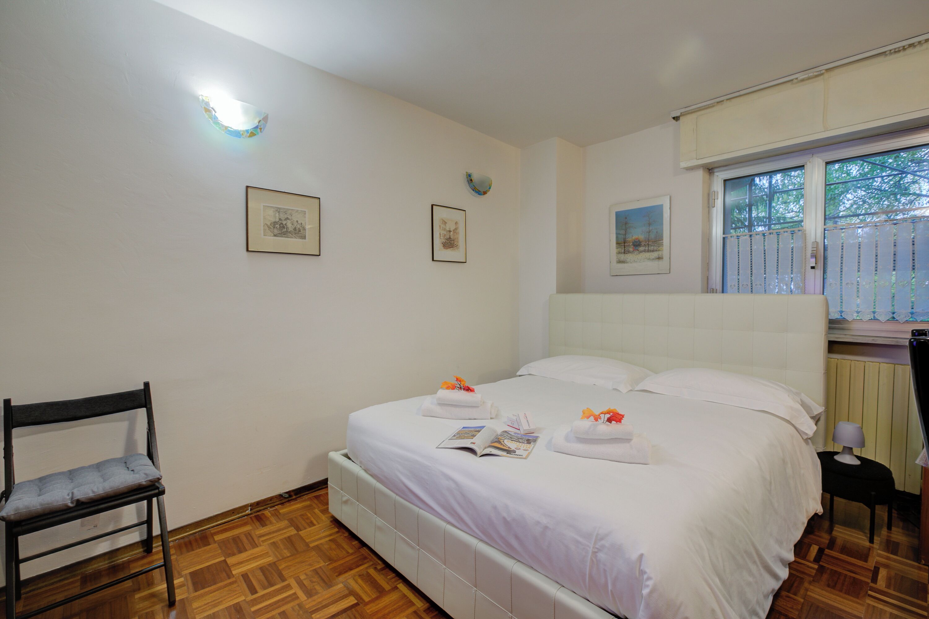 A neatly arranged bedroom with a bed, a chair, and a window.