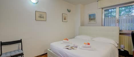 Un dormitorio ordenado con cama, una silla y una ventana.