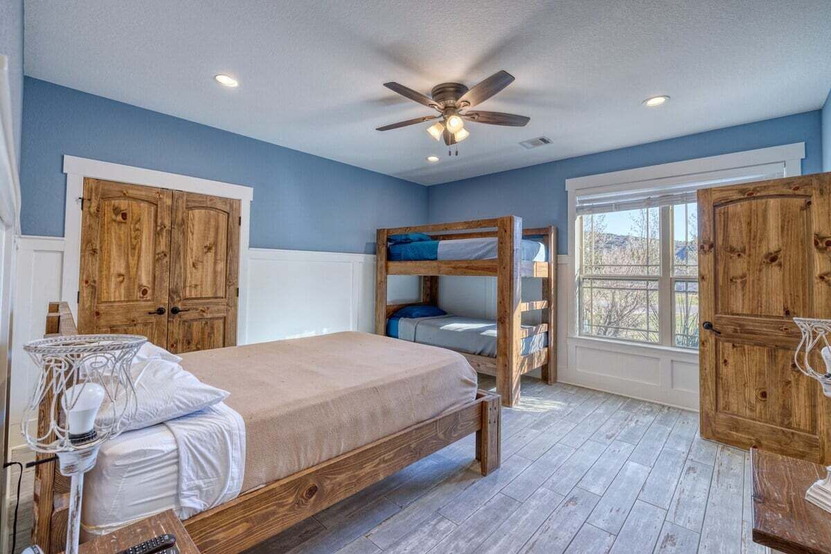 Un dormitorio con literas, un armario de madera y un ventilador de techo.