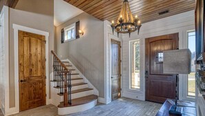 A staircase with a wooden finish, a chandelier, and a wooden door.
