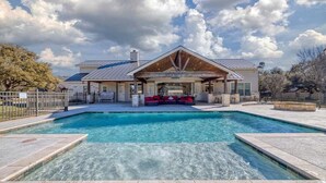 A modern house with a swimming pool, a covered patio, and a fenced yard.