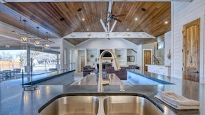 A spacious kitchen with a large island, a ceiling fan, and a view of the outdoor patio area.