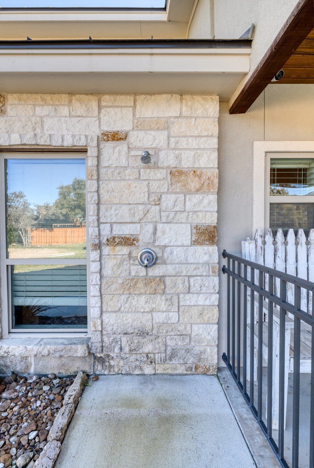 A stone exterior wall with a metal door and a window.