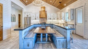 A spacious kitchen with a large island, wooden ceiling, and white cabinetry.