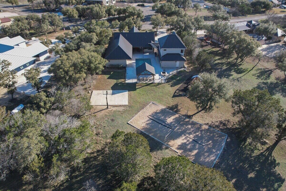 An aerial view of a residential area with multiple houses, including a house with a large solar panel array and a swimming pool.