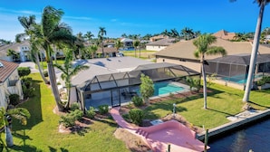 A residential area with a swimming pool, a covered patio, and a boat dock. - Screened Lanai w/ TV: Waterfront Cape Coral Home! (Cape Coral)