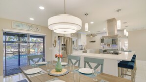 A modern kitchen with a central island, stainless steel appliances, and pendant lighting. - Screened Lanai w/ TV: Waterfront Cape Coral Home! (Cape Coral)