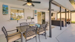 A covered patio area with a dining table and chairs, ceiling fans, and a view into the house. - Screened Lanai w/ TV: Waterfront Cape Coral Home! (Cape Coral)